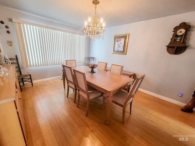 dining space featuring baseboards, an inviting chandelier, and light wood-style floors