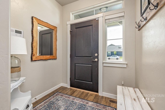 entrance foyer with dark wood-type flooring and baseboards