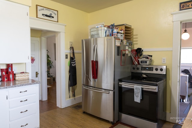 10489 Scotch Pine Rd, Payette, ID 83661 - kitchen featuring appliances with stainless steel finishes, light wood-type flooring, white cabinets, and light stone counters