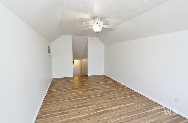 bonus room with light wood finished floors, vaulted ceiling, a textured ceiling, and a ceiling fan