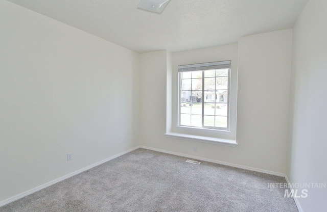 carpeted empty room with baseboards, visible vents, and a textured ceiling