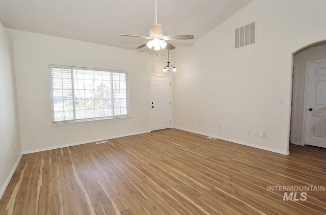 unfurnished room featuring arched walkways, vaulted ceiling, visible vents, wood finished floors, and ceiling fan