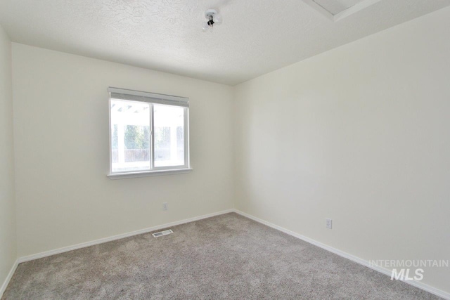 carpeted empty room featuring baseboards, visible vents, and a textured ceiling