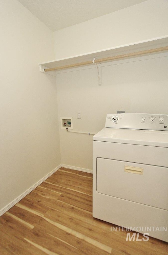 laundry room with light wood-type flooring, baseboards, laundry area, and washer / dryer