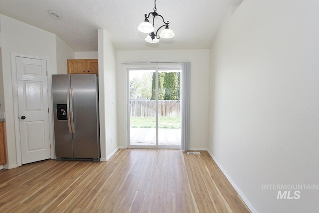 doorway featuring baseboards, a chandelier, visible vents, and light wood-type flooring