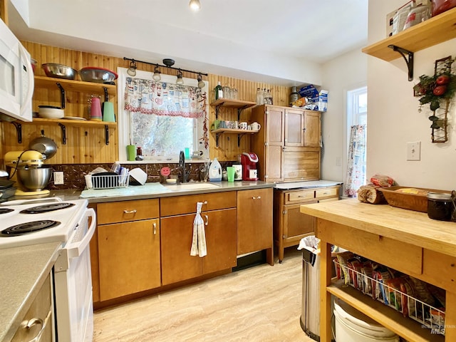 kitchen featuring open shelves, white appliances, light countertops, and a sink