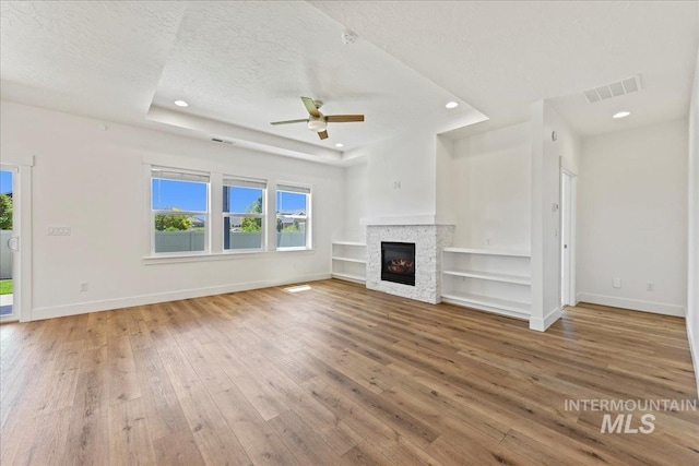 2967 E Diorite St, Nampa, ID 83686 - unfurnished living room featuring hardwood / wood-style flooring, baseboards, a ceiling fan, a fireplace, and a textured ceiling