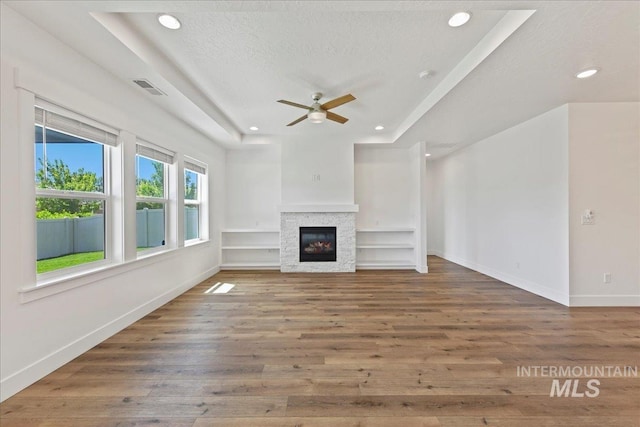 2967 E Diorite St, Nampa, ID 83686 - unfurnished living room featuring a raised ceiling, a ceiling fan, wood finished floors, recessed lighting, and a glass covered fireplace