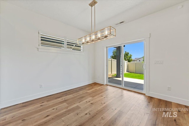 2967 E Diorite St, Nampa, ID 83686 - spare room featuring baseboards, hardwood / wood-style flooring, and a chandelier