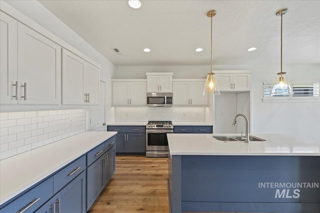 2967 E Diorite St, Nampa, ID 83686 - kitchen with stainless steel appliances, a sink, white cabinets, light wood-style floors, and backsplash