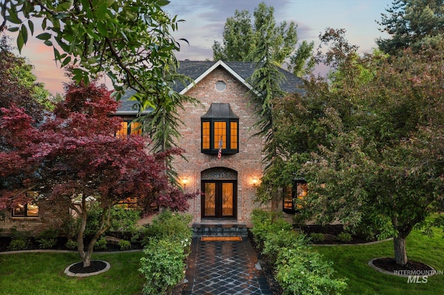 view of front facade featuring french doors, a front yard, and brick siding