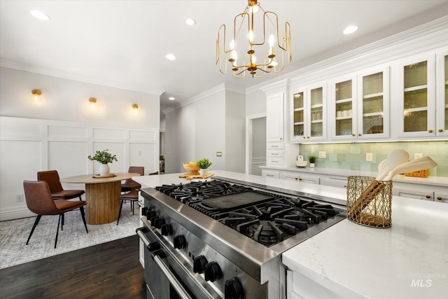 kitchen featuring double oven range, ornamental molding, white cabinets, a decorative wall, and recessed lighting
