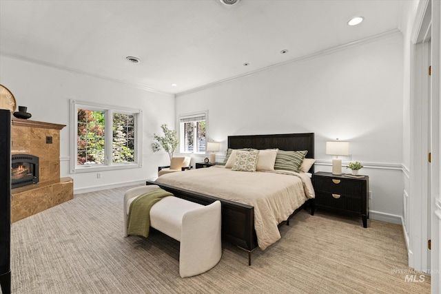 bedroom with light carpet, ornamental molding, a premium fireplace, baseboards, and recessed lighting