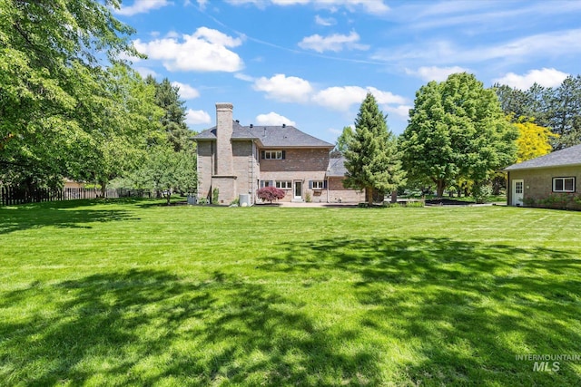 rear view of house featuring a chimney, brick siding, and a patio area