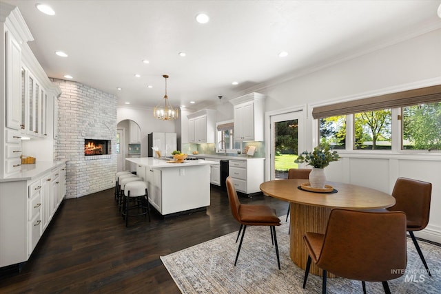 dining room with ornamental molding, dark wood-style flooring, recessed lighting, and a brick fireplace