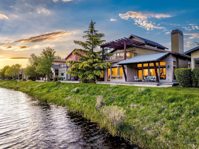 1337 E Lone Shore Dr, Eagle, ID 83616 - rear view of house with a chimney, a water view, metal roof, and a lawn