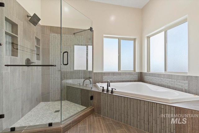 full bath featuring a shower stall, a garden tub, and plenty of natural light
