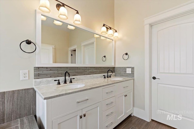 bathroom featuring tasteful backsplash, wood finished floors, a sink, and double vanity