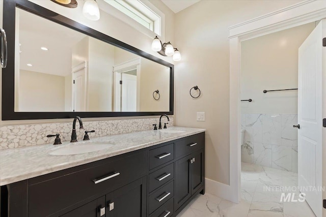 full bathroom with double vanity, marble finish floor, a sink, and a marble finish shower