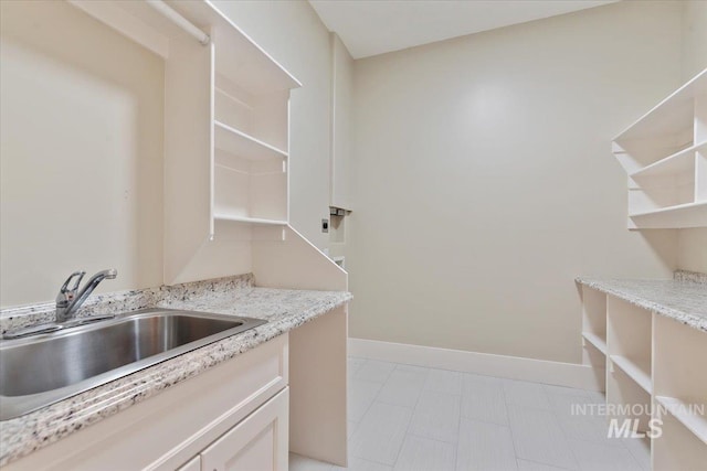 laundry area featuring baseboards and a sink