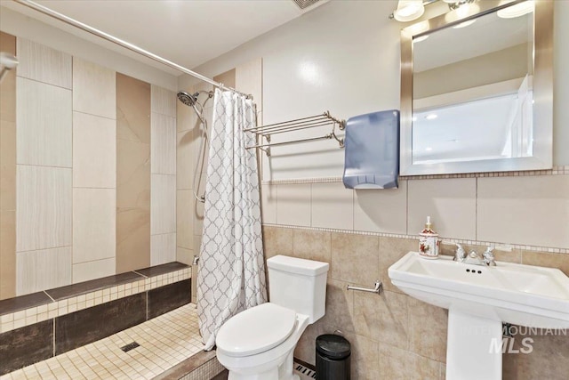 bathroom with a baseboard radiator, a sink, a stall shower, tile walls, and toilet
