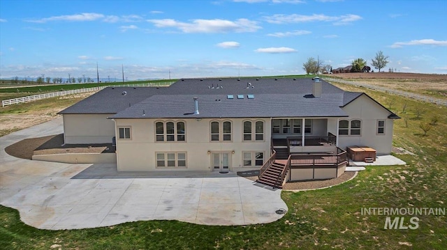 back of property with stairs, a yard, stucco siding, a patio, and a hot tub