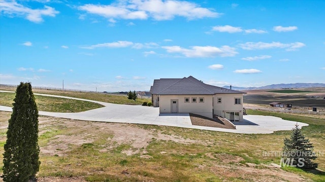 back of house with a patio area, a yard, a mountain view, and stucco siding