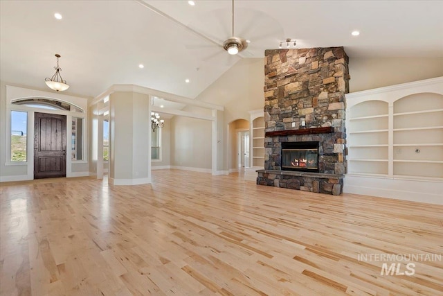 unfurnished living room featuring arched walkways, recessed lighting, wood finished floors, and a fireplace