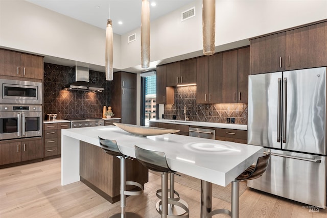 119 S 10th Unit 605, Boise, ID 83702 - kitchen with appliances with stainless steel finishes, wall chimney range hood, dark brown cabinets, tasteful backsplash, and recessed lighting