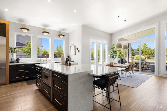 5720 W Little Feather St, Eagle, ID 83616 - kitchen featuring a breakfast bar, light countertops, light wood-type flooring, recessed lighting, and a kitchen island