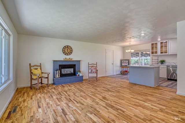 413 S Minnesota Ave, Fruitland, ID 83619 - living room featuring light wood-style floors, a chandelier, and a brick fireplace