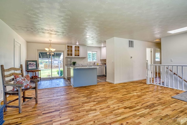 413 S Minnesota Ave, Fruitland, ID 83619 - kitchen with light wood-style floors, a chandelier, glass insert cabinets, and light countertops