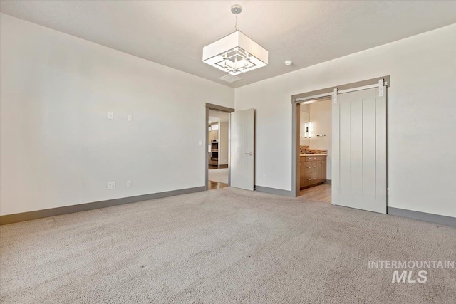 unfurnished bedroom featuring ensuite bathroom and light colored carpet