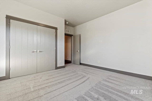 unfurnished bedroom featuring light colored carpet and a closet