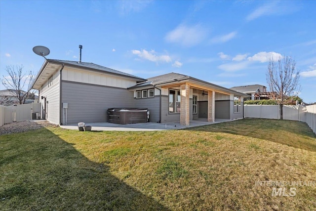 back of house with a patio area, a lawn, and a hot tub