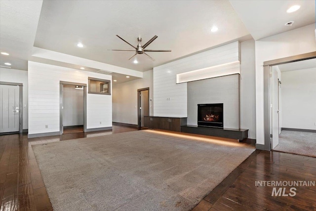 unfurnished living room with elevator, dark hardwood / wood-style floors, and ceiling fan