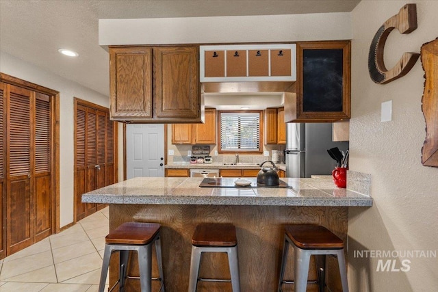 502 Lake Cascade Pkwy Unit 6, Cascade, ID 83611 - kitchen featuring tile countertops, a kitchen breakfast bar, a sink, appliances with stainless steel finishes, and recessed lighting