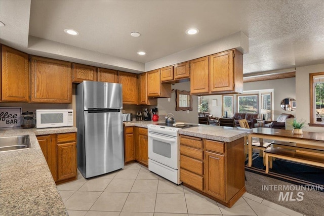502 Lake Cascade Pkwy Unit 6, Cascade, ID 83611 - kitchen with white appliances, brown cabinetry, light countertops, a peninsula, and light tile patterned floors