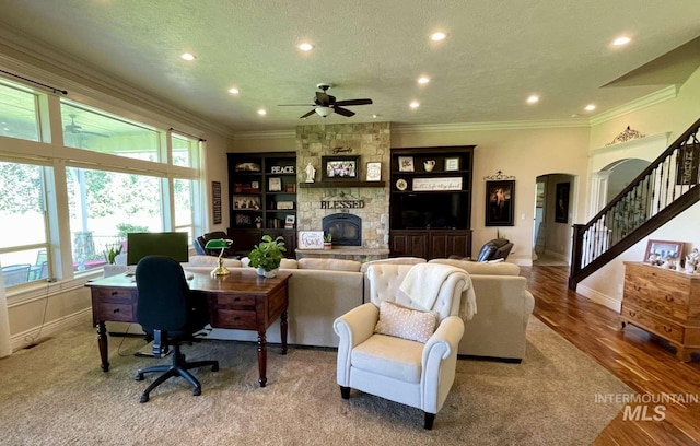 home office featuring a textured ceiling, wood finished floors, arched walkways, a fireplace, and crown molding