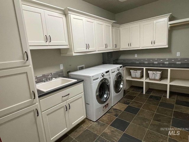 clothes washing area with a sink, cabinet space, and washing machine and dryer