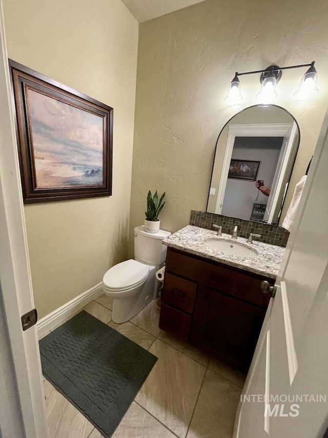 bathroom with backsplash, baseboards, toilet, and vanity