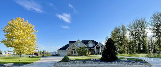 view of front of home featuring stone siding, a garage, driveway, and a front yard