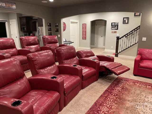 carpeted home theater featuring baseboards and arched walkways