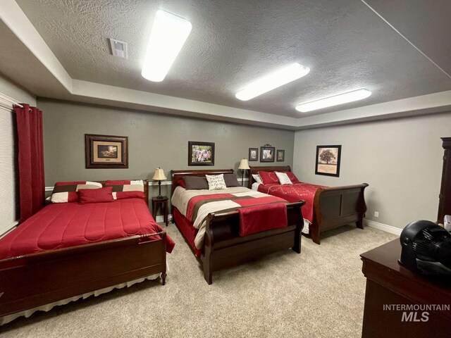 carpeted bedroom featuring visible vents, a textured ceiling, and baseboards