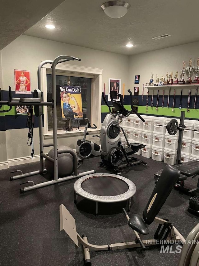 exercise room with visible vents and a textured ceiling