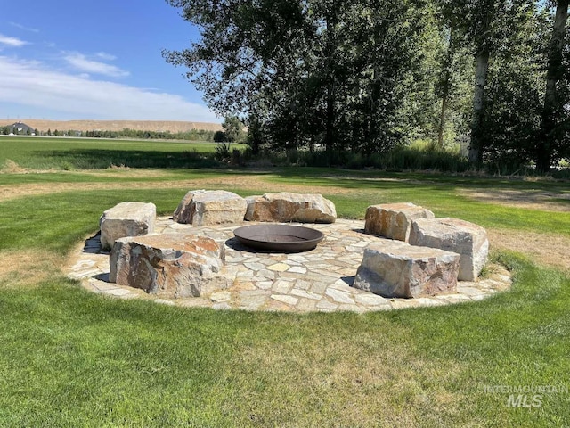 view of yard featuring a rural view, a patio area, and a fire pit