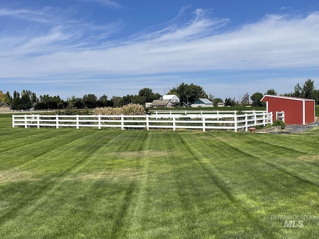 view of yard featuring a rural view, an outdoor structure, and fence