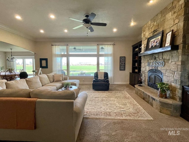 living room featuring ornamental molding, ceiling fan with notable chandelier, a fireplace, baseboards, and light colored carpet