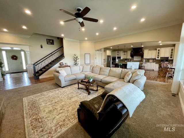 living room with stairs, a ceiling fan, recessed lighting, and ornamental molding