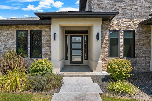 doorway to property with stone siding and stucco siding